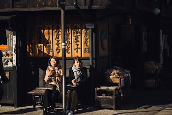 two women sitting on bench outdoor during daytime