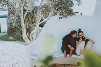 Two Women Sitting On White Bench While Looking At Camera