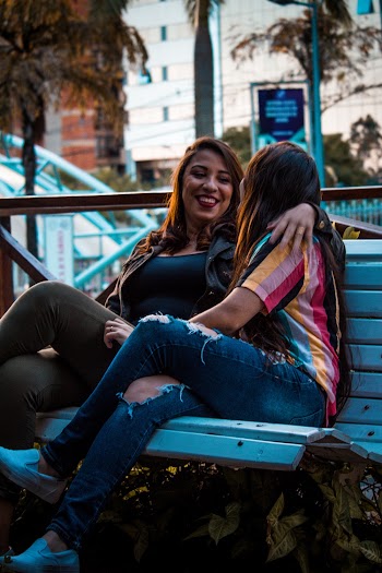 Two Women Sitting on White Wooden Bench