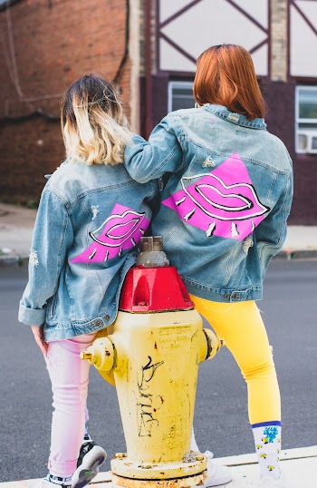 Two Women Sitting on Yellow Fire Hydrant
