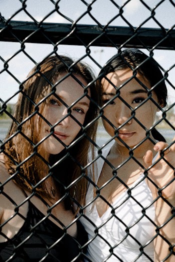 Two Women Standing Behind Chain-link Fence
