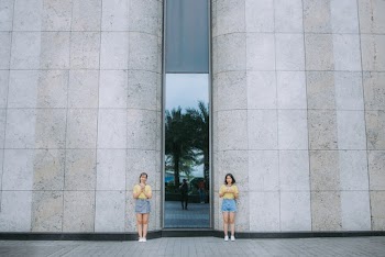 Two Women Standing Beside Brown Concrete Building