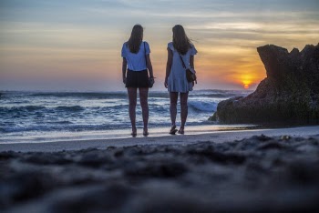 Two Women Standing Near Body of Water
