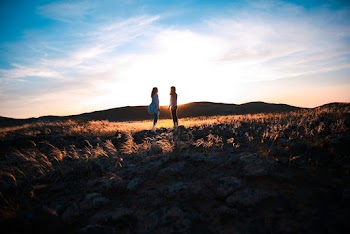 Two Women Standing on Brown-grass Field
