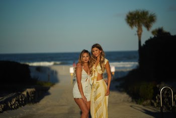 Two Women Standing on Street Near Body of Watr