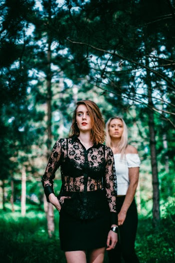 Two Women Standing Under Green Trees
