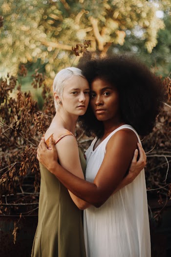 Two Women Standing Wearing Dresses