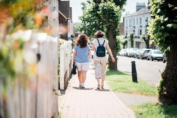 two women walking down sidewalk near fence