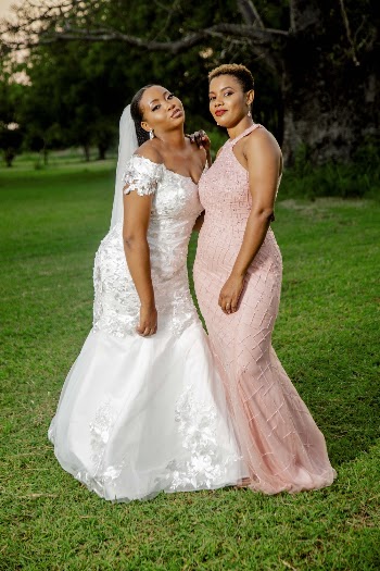 Two Women Wearing Gowns Standing on Grass