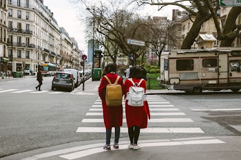 Two Women Wearing Red Coats With Backpacks 