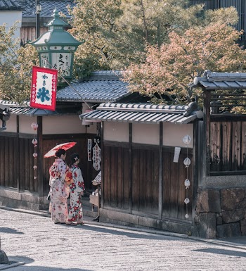 Two Women Wearing Traditional Dresses Standing Near House