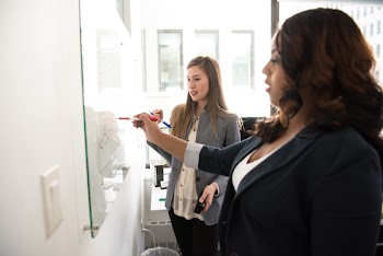 Two Women Writing on the White Board
