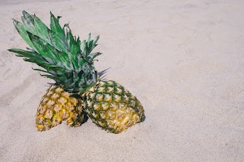 Two Yellow Pineapple Fruits Stocked on Sand