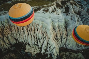 two yellow-red-black-teal hot air balloons floating over terrain