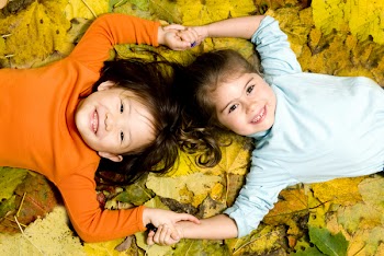 Two young girls playing in the Autumn Leaves.