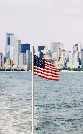 U.S.A. flag on pole near sea under cloudy sky