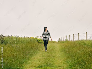 UK, Female hiker walking in grassy field