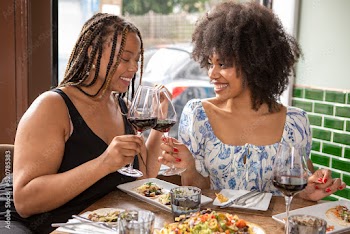 UK, London, Smiling friends toasting with red wine at restaurant table