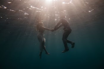 underwater photography of woman and man while holding hands