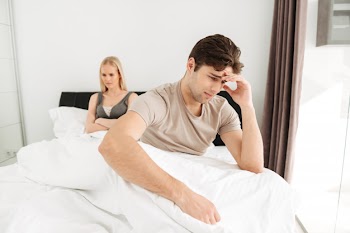 Upset man sitting with his sad woman in bed at home Free Photo