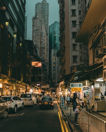 Vehicle on Street in Between High-rise Buildings With Stores on the Bottom