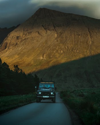 Vehicle Passing by Road With Mountain Background