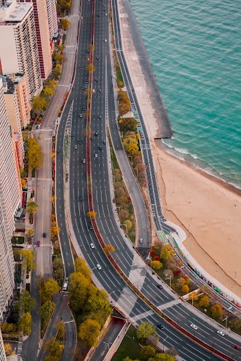 Vehicles on Road Beside Body of Water and High Rise Buildings