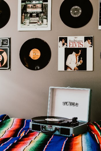 Victrola record player playing music on a bed. Elvis record player in the background.