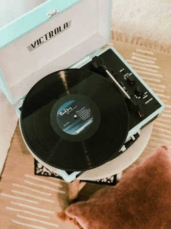 Victrola turquoise suitcase record player playing a black record in a bedroom.