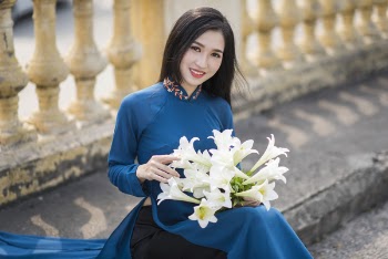 Vietnamese girl in Ao Dai sitting with flower