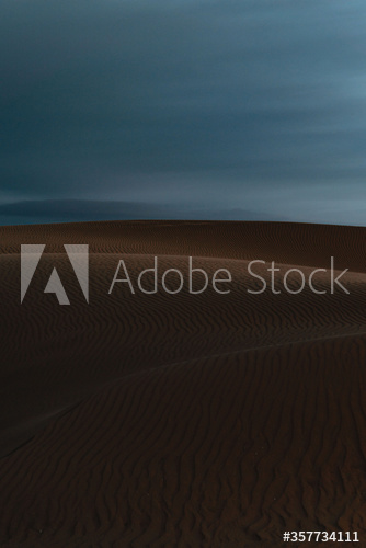 View of sand dunes against stormy clouds