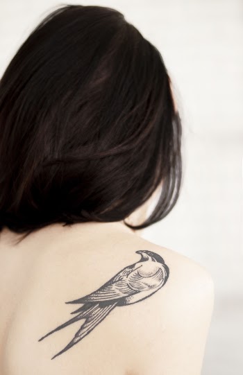 View of Woman's Back With Bird Tattoo on Right Shoulder