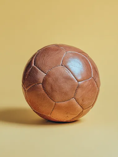 Vintage Leather Soccer Ball on Pastel Yellow Background Vintage Leather Soccer Ball on Pastel Yellow Background