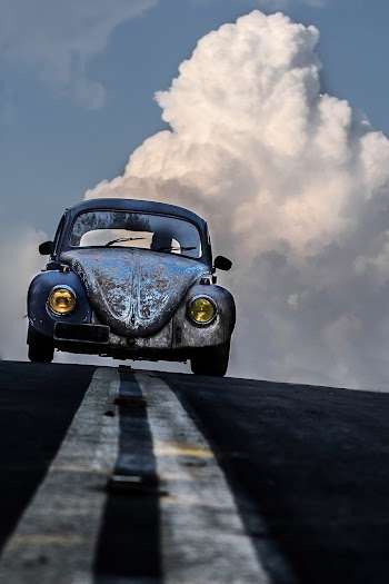 Volkswagen Beetle on Road Against White Clouds