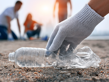 Volunteer Picking Up Plastic Bottle on a Beach