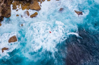 Walking across this gap is an impressive feat.
Arthur Pera takes a break in the middle of a 173m highline on the coast of Sydney, AUS. He's wearing a harness and proper safety equipment is used to ensure there is minimal danger.