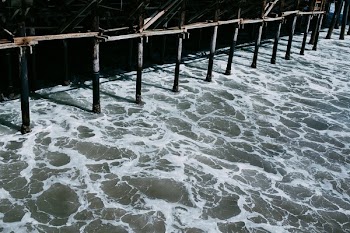 Water Flowing Underneath The Shadowy Pier