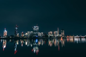 water mirror reflection of lighted high-rise buildings at night time