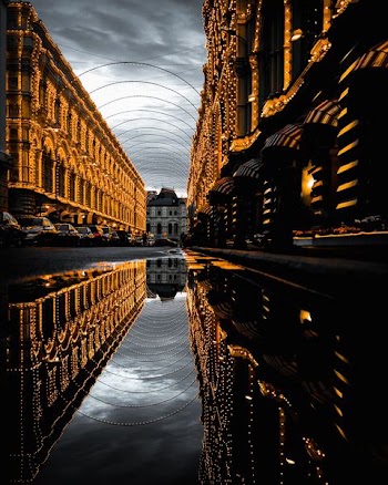water on asphalt road with reflection of fully-decorated buildings under cloudy sky