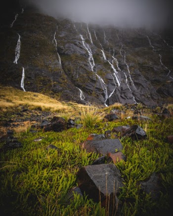 Water runs down the side of cliffs in New Zealand near Milford Sound. 