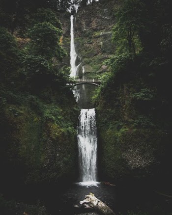 waterfall in between mountains with bridge