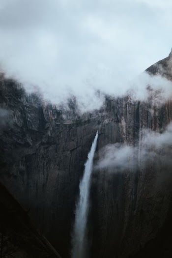 waterfall under white clouds at daytime