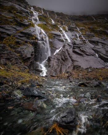 Waterfalls near Milford Sound, New Zealand. One of the most amazing experiences I've had traveling. This was on the road to Milford Sound in New Zealand. It is one of the rainest places on Earth and it was absolutely pouring when I was there. Waterfalls were forming literally everywhere around, just coming down the sides of the mountains. 