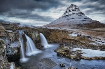 waterfalls near snowy mountain during daytime