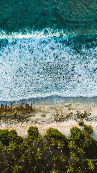 Waves crash on a beach on a tropical Maldivian island