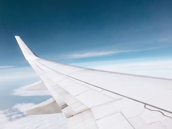 white airplane flying over white clouds
