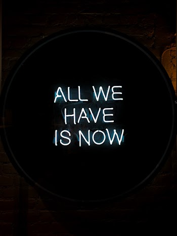 White All We Have Is Now Neon Signage on Black Surface