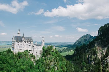 White and Black Concrete Castle Surrounded by Green Trees Under Blue and White Sky