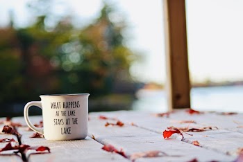 White and Black Mug On A Wooden Surface With Scattered Dry Leaves