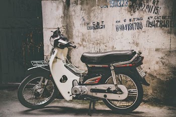 white and black underbone motorcycle parked near the wall